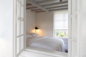 a white bedroom with a bed and a window at Het Witte Kasteel in Loon op Zand