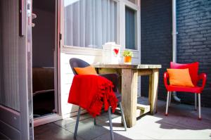 a table and chairs with red and orange cushions on a patio at B&B - Pension Perruque in Koudum