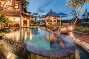 een overloopzwembad met stoelen en parasols naast een huis bij A home, like a dream in Ubud