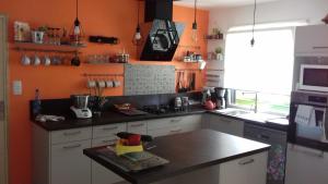 a kitchen with orange walls and a black counter top at petit coin au calme in Baulon +7 photos