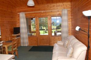 sala de estar con sofá blanco en una sala de madera en Cosy Rowan woodland lodge no1, en Killin