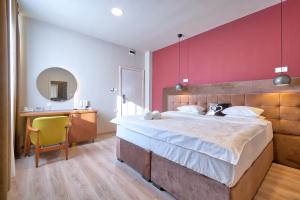ein Schlafzimmer mit einem großen Bett und einer roten Wand in der Unterkunft Boutique Hotel St Georgije in Banja Luka