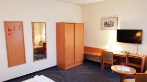 Habitación de hotel con escritorio y espejo en Hotel Altberesinchen en Frankfurt/Oder
