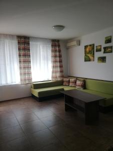 a living room with green furniture and two windows at Apartamenti Zhelezovi in Pomorie
