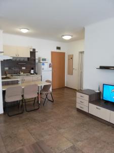 a kitchen with a table and chairs and a television at Apartamenti Zhelezovi in Pomorie
