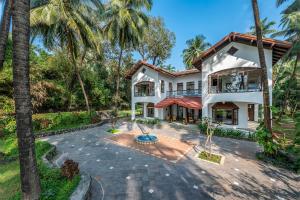 an exterior view of a house with palm trees at SaffronStays Thalassea, Alibaug - picturesque sea-facing villa with colonial decor in Alibaug