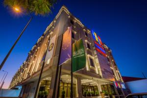 un bâtiment avec drapeaux devant lui la nuit dans l'établissement Ewaa Express Hotel - Gaber, à Riyad