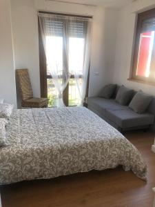 1 dormitorio con cama, sofá y ventana en A casa di Titty en Somma Lombardo