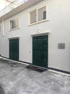two green doors on the side of a white building at La Corte del Re Borbone in Caserta