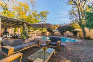 un patio con sofá y sombrilla junto a la piscina en De Leeuwenhof Estate, en Paarl