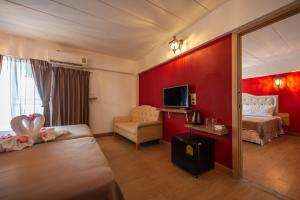 a hotel room with two beds and a red wall at @42 Residence in Bangkok