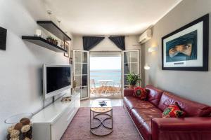 sala de estar con sofá de cuero rojo y TV en Apartment in front of the Beach, en Pineda de Mar