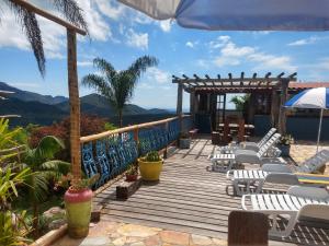 eine Holzterrasse mit Stühlen und einem Sonnenschirm in der Unterkunft Pousada Ecologica Vale das Cores in Lavras Novas