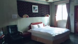 pokój hotelowy z łóżkiem i krzesłem w obiekcie 雲林東勢御花園汽車旅館 w mieście Dongshi-Yulin 