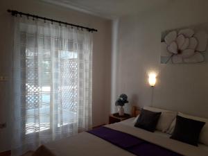 a bedroom with a bed and a window with white curtains at Delfin Apartments in Sveti Juraj