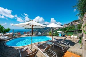 a pool with chairs and umbrellas and the ocean at Ville Olimpo in Positano