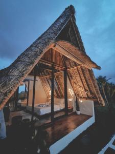 a resort with a bed with a thatched roof at Capila Villa Bali in Canggu