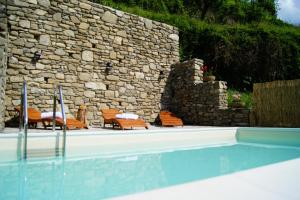 a swimming pool with chairs and a stone wall at Ca'Luni in Casola in Lunigiana