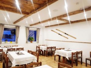 a restaurant with white tables and chairs and wooden ceilings at Zirbenhof in Innerkrems