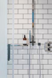 a shower with a hose on a white brick wall at Superior Stays Rosewell House - Bath City Centre in Bath