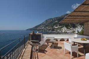 Un balcón con sillas y mesas y vistas al océano. en Hotel Luna Convento, en Amalfi