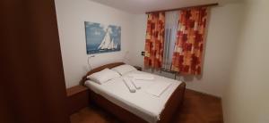 ein kleines Bett in einem kleinen Zimmer mit einem Fenster in der Unterkunft Apartment Krajacic in Krk