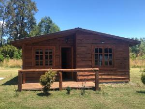 Cabaña de madera con porche en un campo en Cabaña Trasmahue, en Villarrica