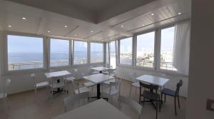 a dining room with tables and chairs and windows at le terrazze sul mare gallipoli centro in Gallipoli