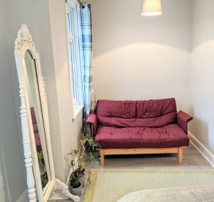 un divano rosso in una stanza con specchio di TopHome West Hampstead a Londra