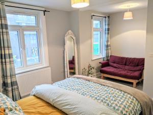 1 dormitorio con cama, espejo y silla en TopHome West Hampstead, en Londres