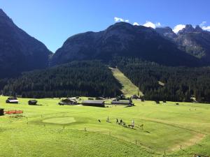 a group of people playing golf in a field with mountains at Appartamenti De Betta in Sappada