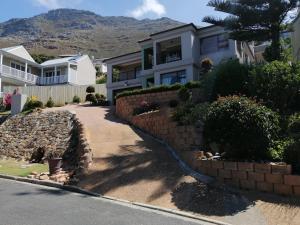 a house with a retaining wall and a driveway at Froggy at the Pond in Simonʼs Town