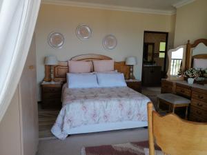 a bedroom with a bed with pink pillows and a mirror at Froggy at the Pond in Simonʼs Town