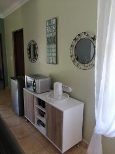 a room with a counter with a microwave and a mirror at Froggy at the Pond in Simonʼs Town
