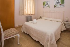 ein Schlafzimmer mit einem weißen Bett und einem Stuhl in der Unterkunft Apartamentos turisticos Avila Villa Carmen III in Avila