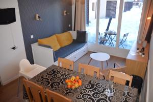 Un comedor con una mesa y un sofá. en Pied de pistes, résidence 3 étoiles tout confort dont terrasse et piscine, en Valmeinier