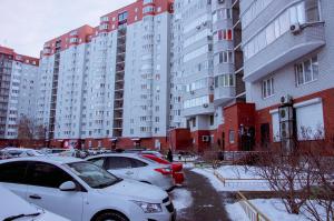 a parking lot with cars parked in front of tall buildings at Studio in the center VLKSM 13 in Tyumen