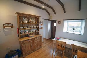 a kitchen with a wooden cabinet and a table at Red Stonecutters Cottage, Doolin in Carrowauff