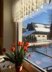 eine Vase aus Blumen in einem Fenster mit Aussicht in der Unterkunft U Wiesi in Poronin