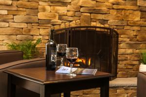 a bottle of wine and two glasses on a table in front of a fireplace at Golden Apple Inn in Glen