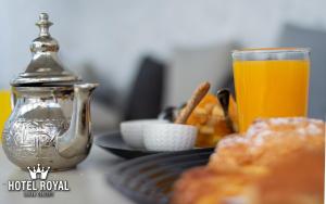 Hôtel Royal Urban Concept في فاس: طاولة مع طبق من الطعام وكأس من عصير البرتقال