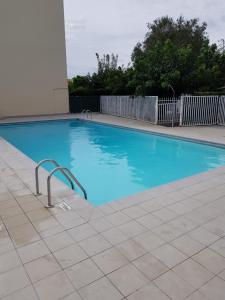 a large blue swimming pool in front of a building at Studio cabine Canet Plage Parking in Canet-en-Roussillon
