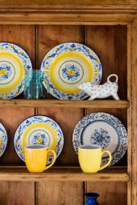 a shelf with yellow and blue plates and cups at Blue Stonecutters Cottage, Doolin in Carrowauff