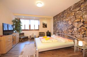 a bedroom with a stone wall with a bed and a tv at Apartmany Rudolf in Spišská Nová Ves