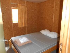 Cette petite chambre comprend un lit et une fenêtre. dans l'établissement Camping le Nid du Parc, à Villars-les-Dombes