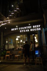 a man standing in front of a steak house at night at The BoB Hostel in Bangkok