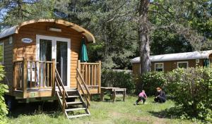 una casa pequeña con un porche y dos personas delante de ella en Camping le Nid du Parc en Villars-les-Dombes