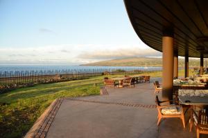 a patio with tables and chairs and a view of the ocean at Nayara Hangaroa in Hanga Roa