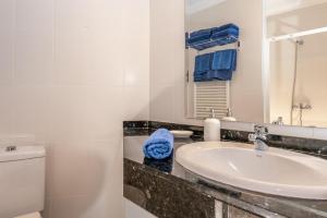 ein Badezimmer mit einem Waschbecken, einem WC und einem Spiegel in der Unterkunft Residencial Playa Mar in Cala Mendia