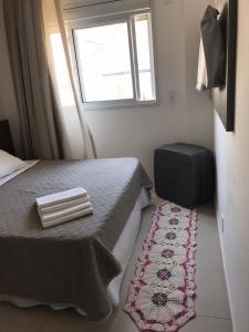 a bedroom with a bed and a window and a rug at Gaivotas Apart - Frente Mar in Florianópolis